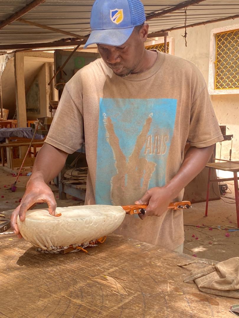 Abdoulaye Traoré Diop sanding a xalam in his Dakar workshop